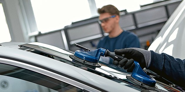 Zwei Autoglaser installieren eine Windschutzscheibe