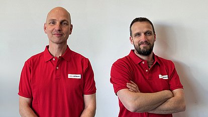 Zwei junited AUTOGLAS Partner mit rotem Poloshirt