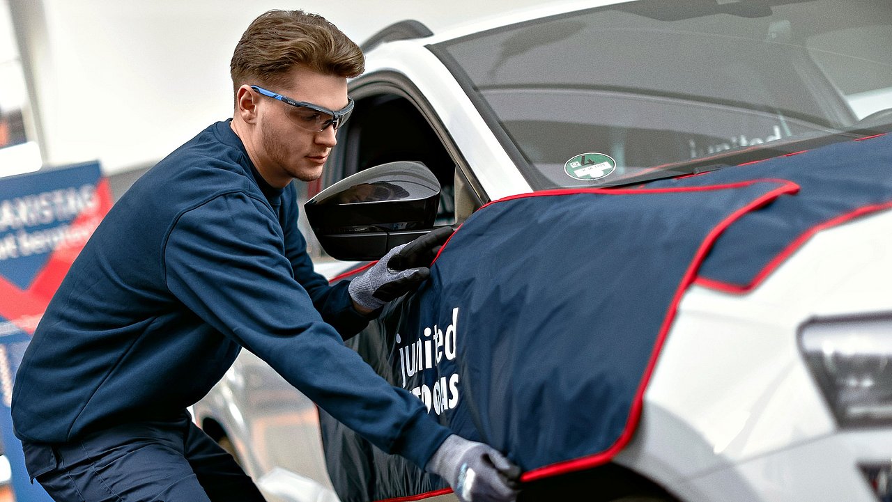 Autoglaser bereitet ein Fahrzeug für Reparaturarbeiten vor.