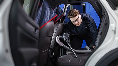 Autoglaser saugt das Innere eines Autos