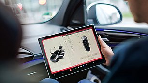 Mitarbeiter sitzt im Auto mit einem Tablet in der Hand und prüft essenzielle Einstellungen